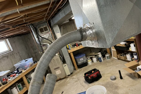 Vacuum hose connected to a return air duct in an unfinished basement