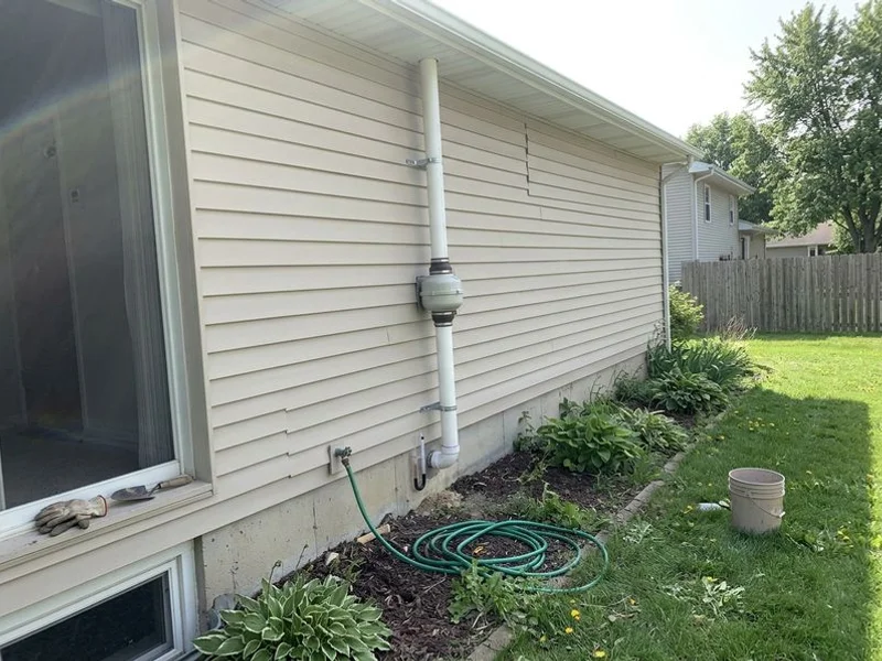Finished radon mitigation system on the side of an Iowa suburban home