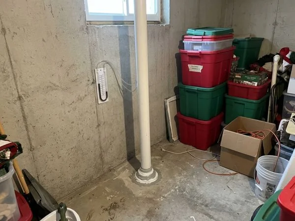 Sealed radon suction point with U-tube manometer in a basement corner